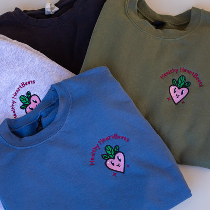Four sweatshirts in different colors with a logo on a white surface